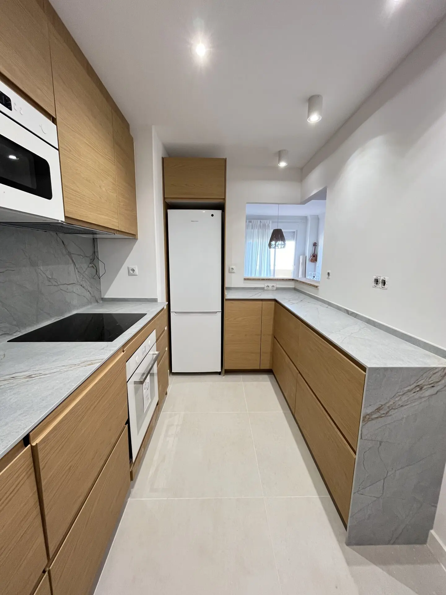 Renovated kitchen with wood cabinets and grey worktops, shown on the LookHome projects page