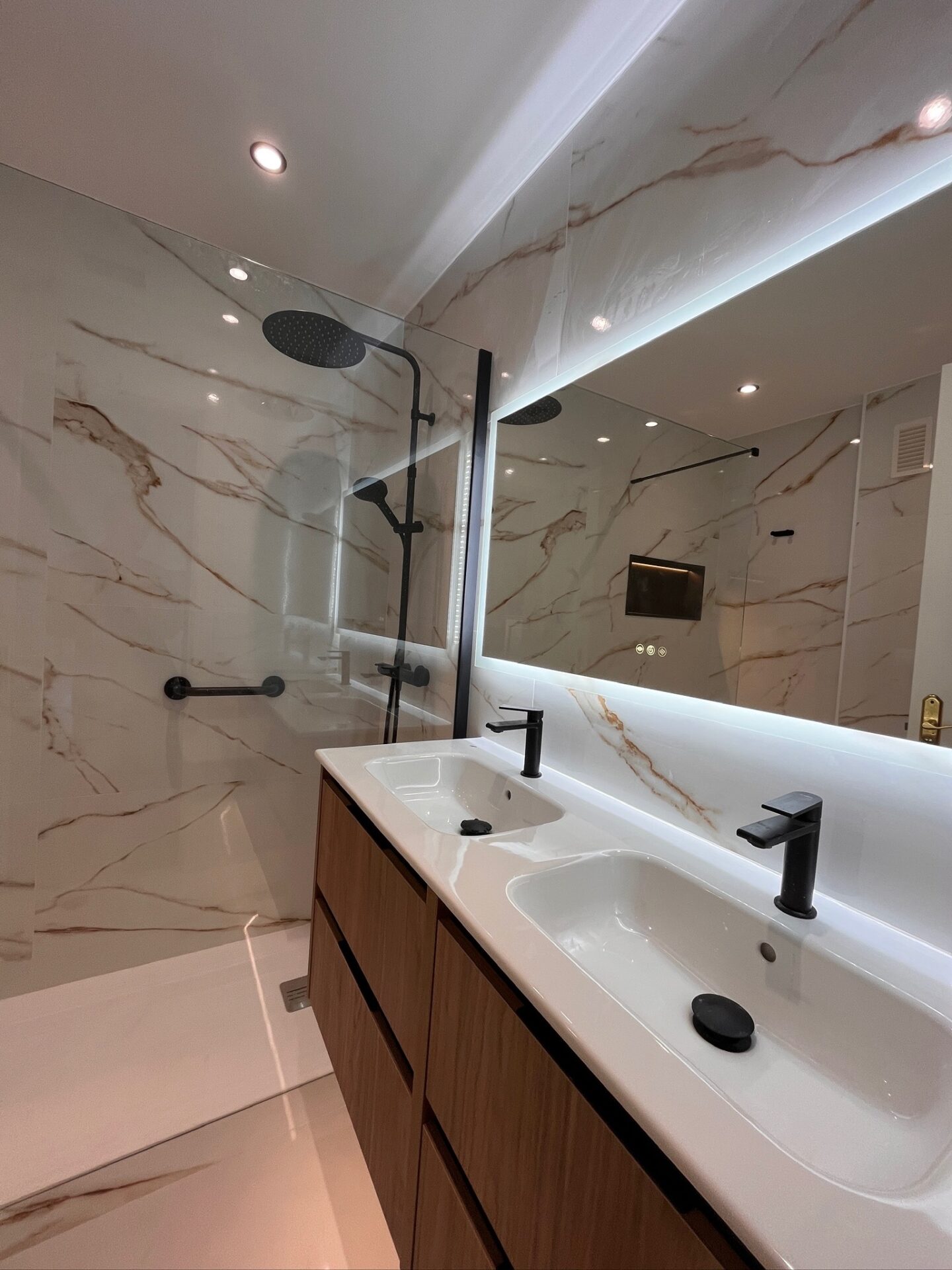 Finished bathroom with marble-look wall surfaces, walk-in shower and double vanity